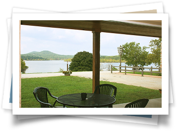 A patio with a table and chairs overlooking a lake