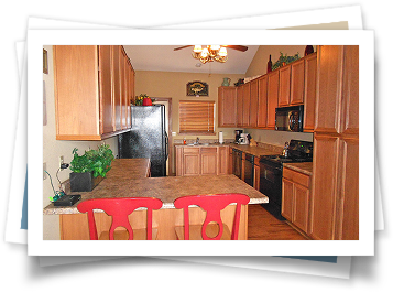 A picture of a kitchen with wooden cabinets and red chairs