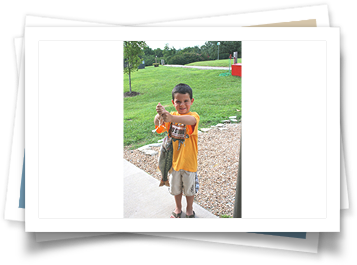 A young boy in a yellow shirt is holding a fish