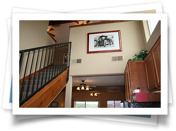 A picture of a house with a picture on the wall above the stairs