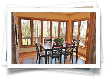 A dining room with a table and chairs and lots of windows