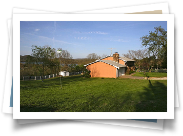 A picture of a house in the middle of a grassy field