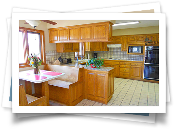 A kitchen with wooden cabinets and a table with a vase of flowers on it