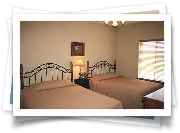 A bedroom with two beds and a window with blinds