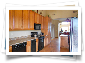 A kitchen with wooden cabinets , black appliances and granite counter tops.