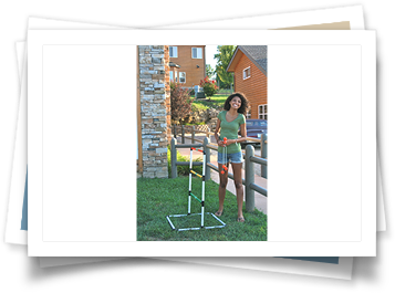 A woman is standing in front of a fence holding a hose