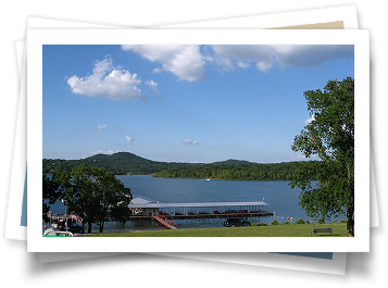 A picture of a lake with a dock and mountains in the background