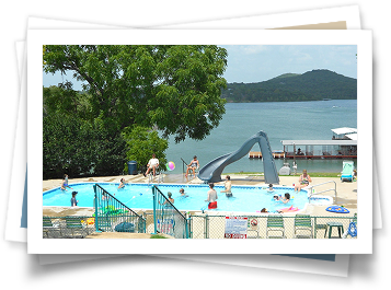 A group of people are playing in a swimming pool near a lake.