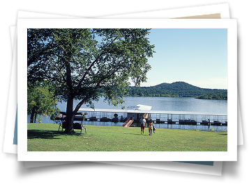 A couple standing in front of a lake with a dock in the background