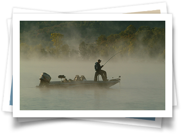 A man is fishing on a boat in the fog.