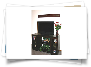 A picture of a tv stand with a vase of flowers on it