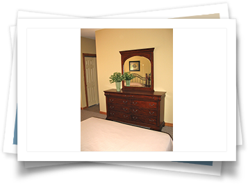 A picture of a bedroom with a dresser and mirror