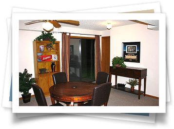 A room with a table and chairs and a ceiling fan