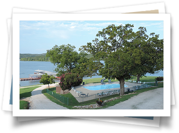 A picture of a swimming pool surrounded by trees and a lake.