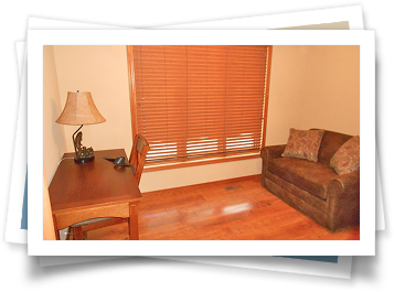 A picture of a living room with a couch and a desk