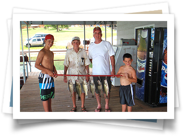 A group of people are standing on a dock holding fish.