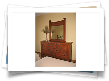 A picture of a bedroom with a dresser and mirror