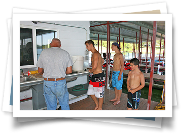 A group of men are standing around a sink in a boathouse