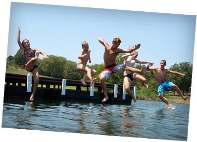 A group of people jumping into a lake from a dock