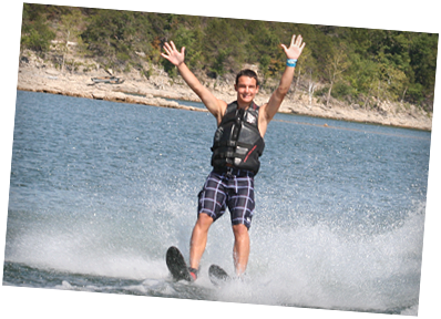 A man in a life jacket is water skiing on a lake