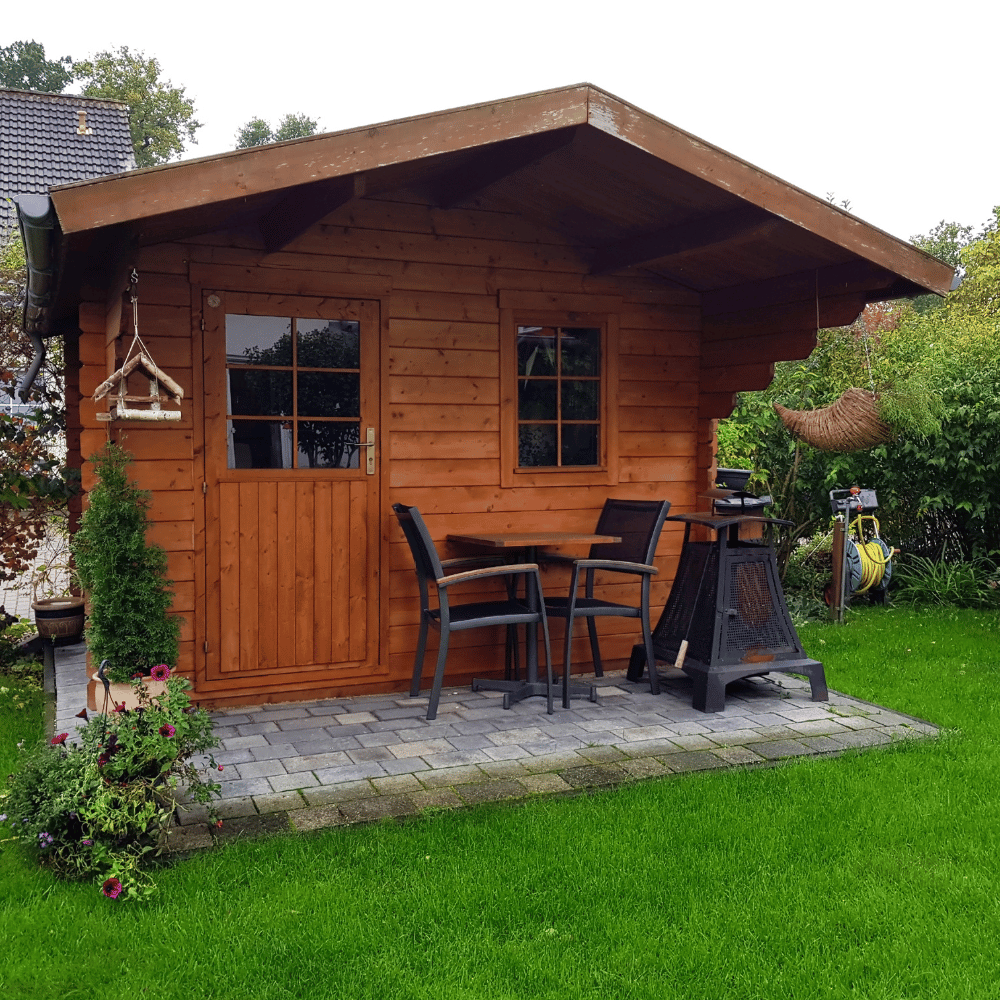 A small wooden house with a table and chairs in the backyard.