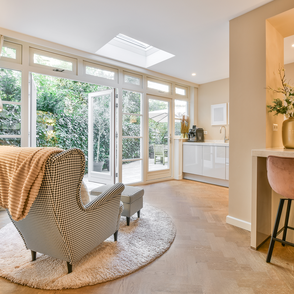 A room with a desk , chair , lamp and sliding glass doors.