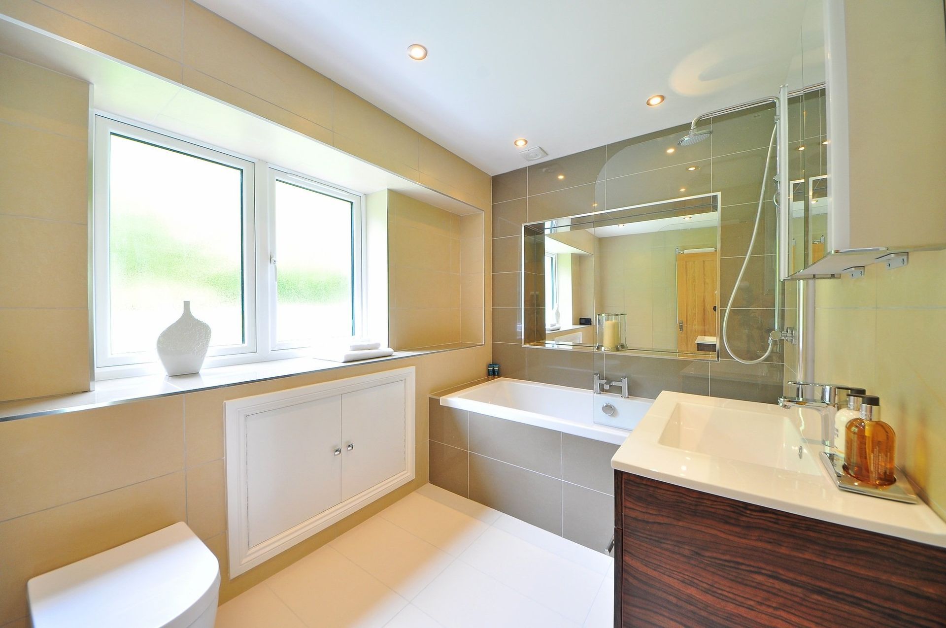 a bathroom with a tub, sink, toilet and window.