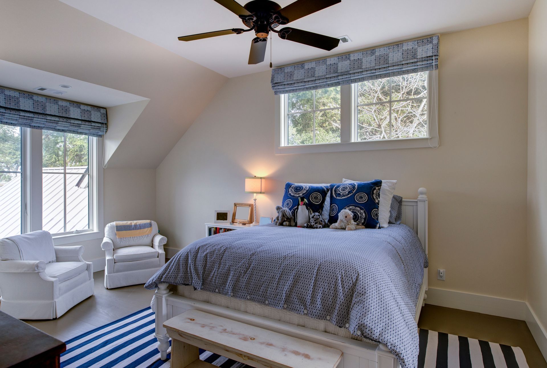 Bedroom with bed, armchairs, window, blue and white decor.