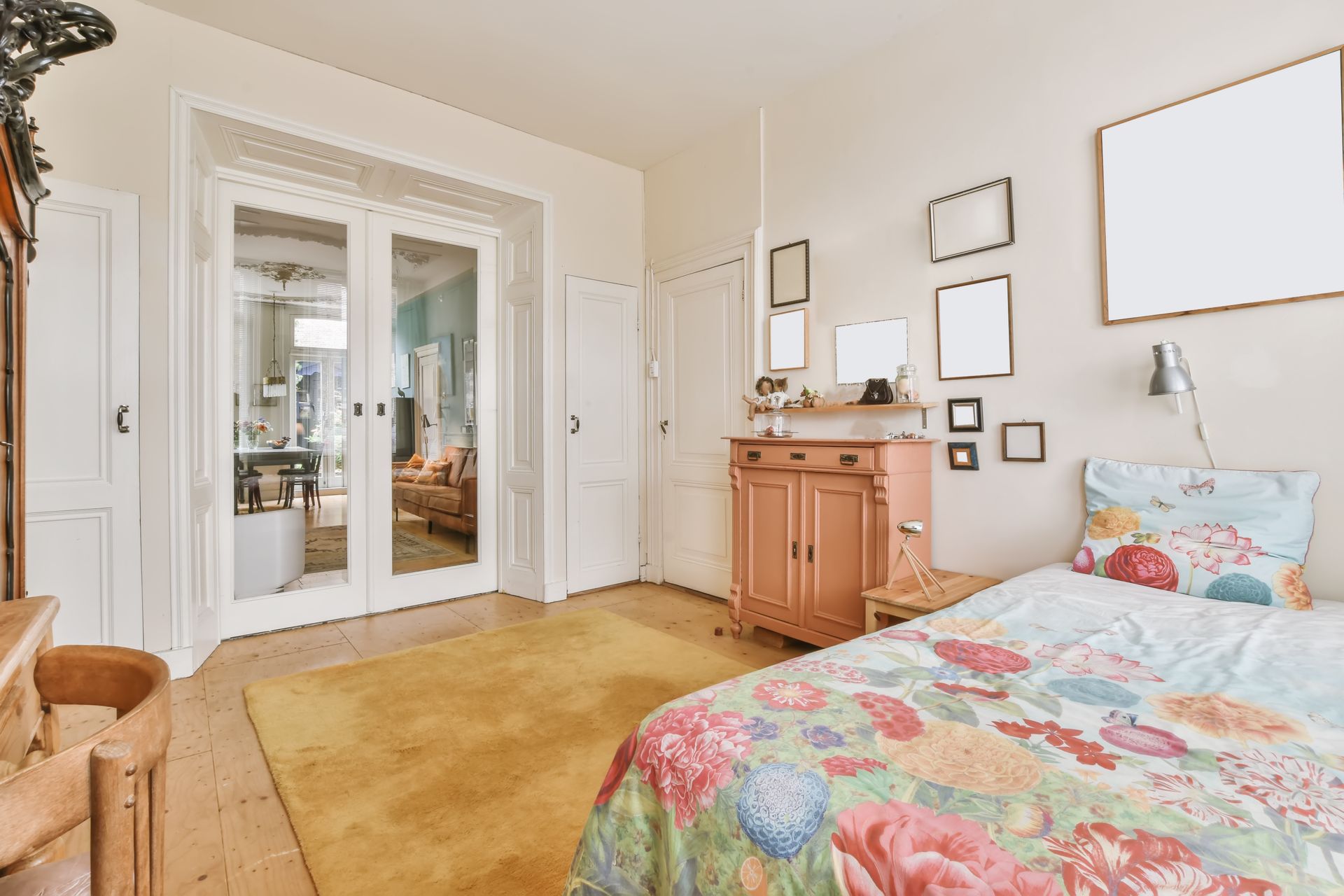 Bedroom with bed, dresser, and doorway to another room. Yellow rug, colorful bedspread.