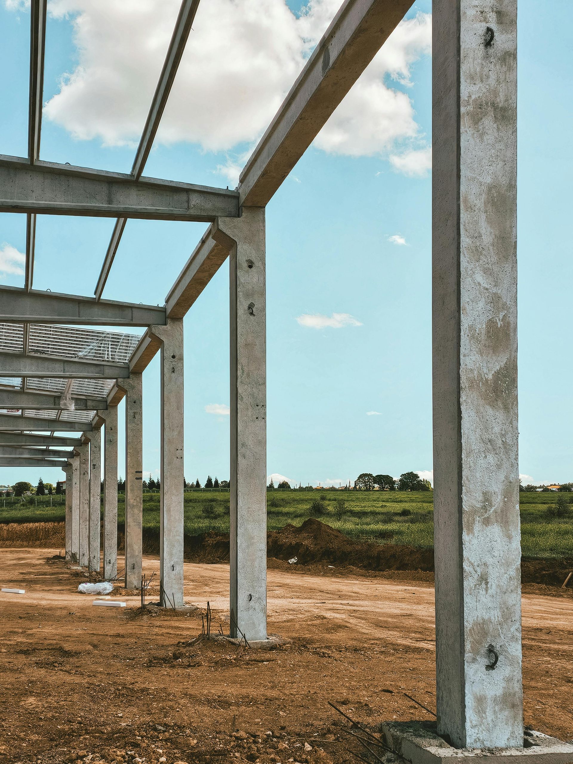 Construction site: concrete pillars and steel beams against a blue sky, setting up the framework of a building.