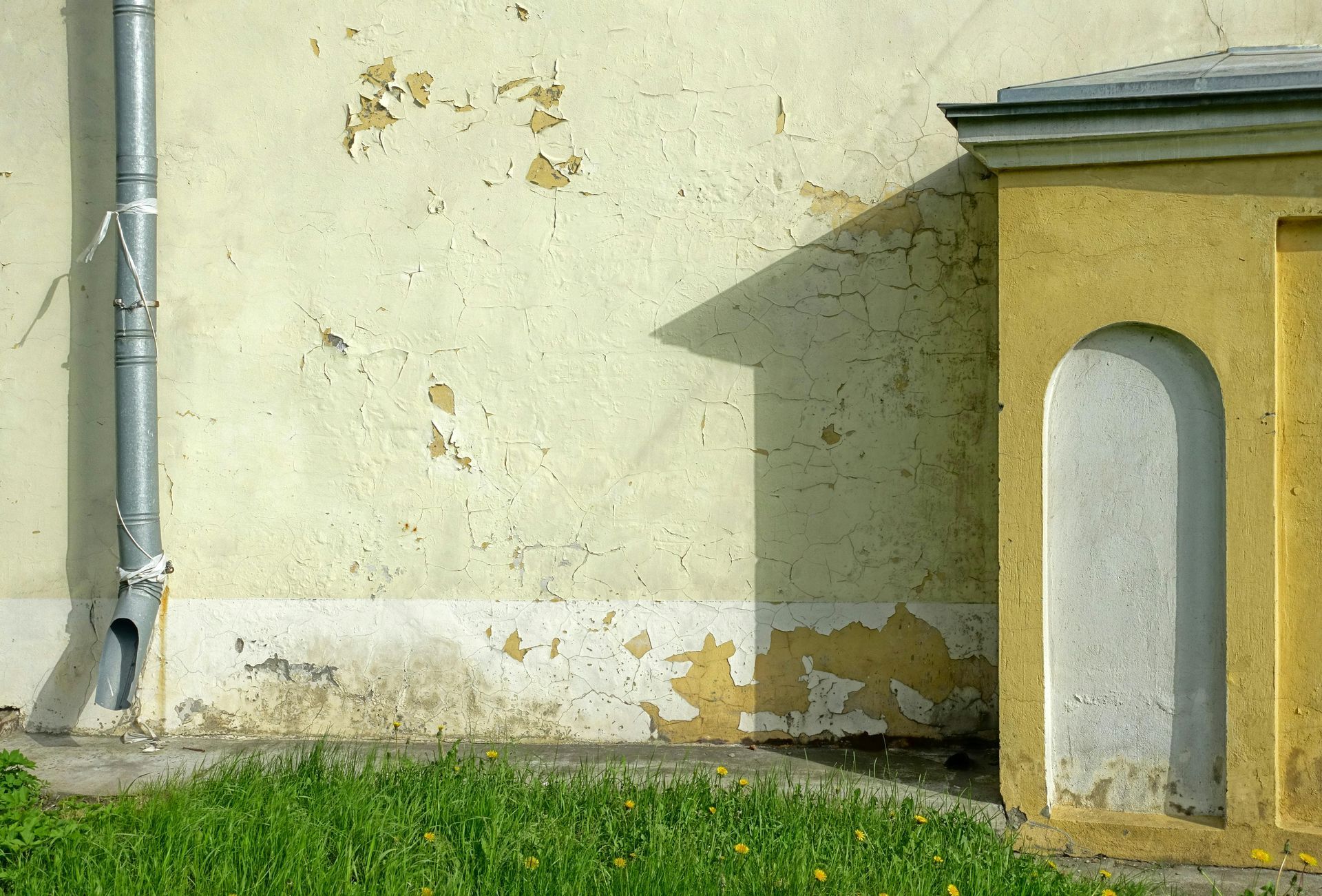 A yellow building with a drain pipe on the side of it