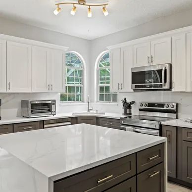 a kitchen with white cabinets, stainless steel appliances, and a large island