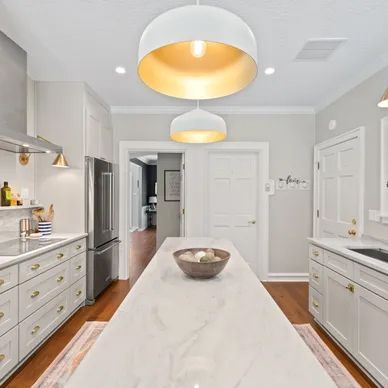 a kitchen with white cabinets, stainless steel appliances, a marble counter top, and a large island