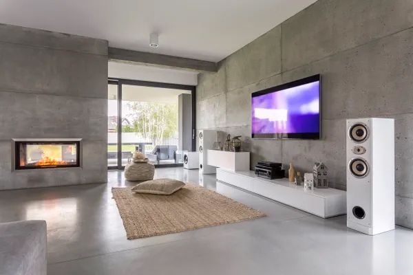 a living room with a fireplace, television, speakers and a rug