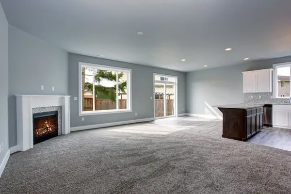 an empty living room with a fireplace and sliding glass doors