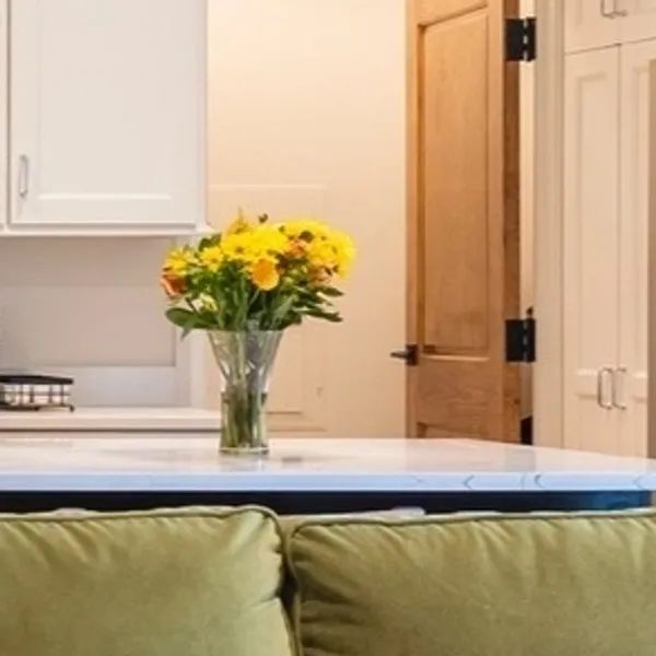 a vase of yellow flowers is sitting on a table in a kitchen