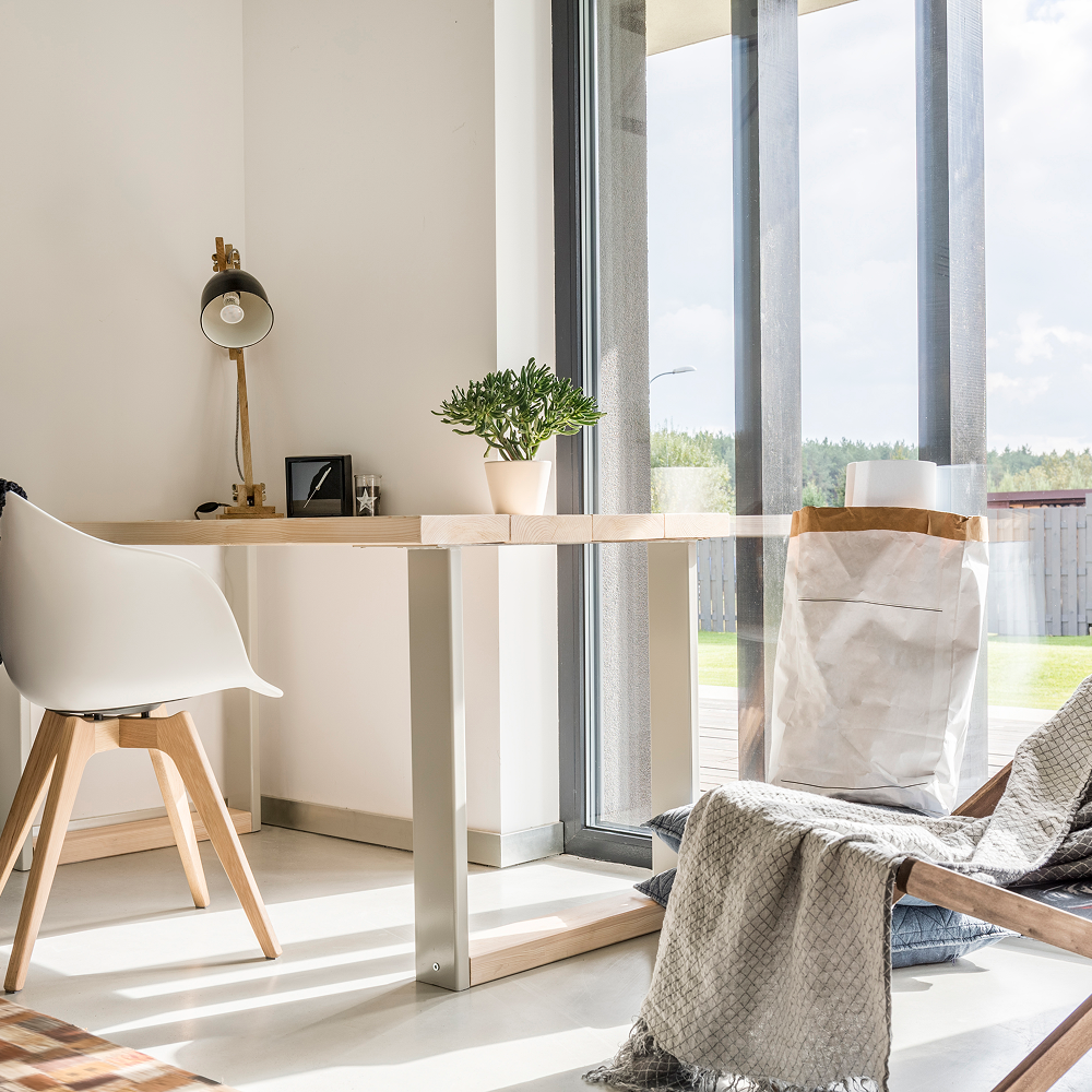 A room with a desk , chair , lamp and sliding glass doors.
