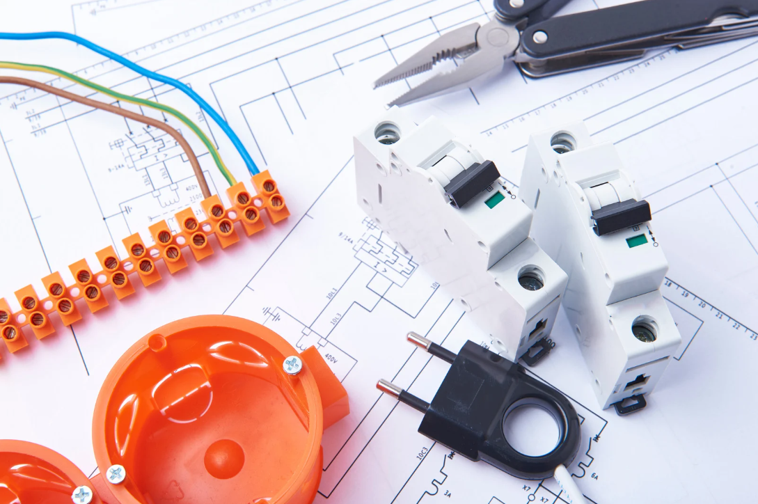 Electrical components, wiring, and tools arranged on a blueprint.