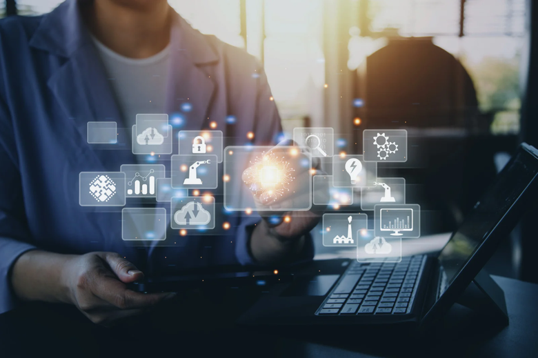 Person using a laptop with digital icons floating above, suggesting data analysis or technology usage.