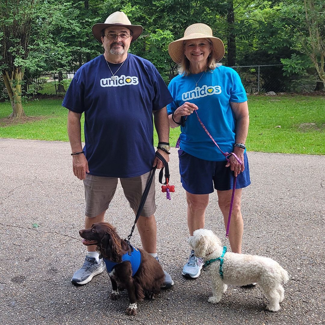 Two partners pose with their two dogs.