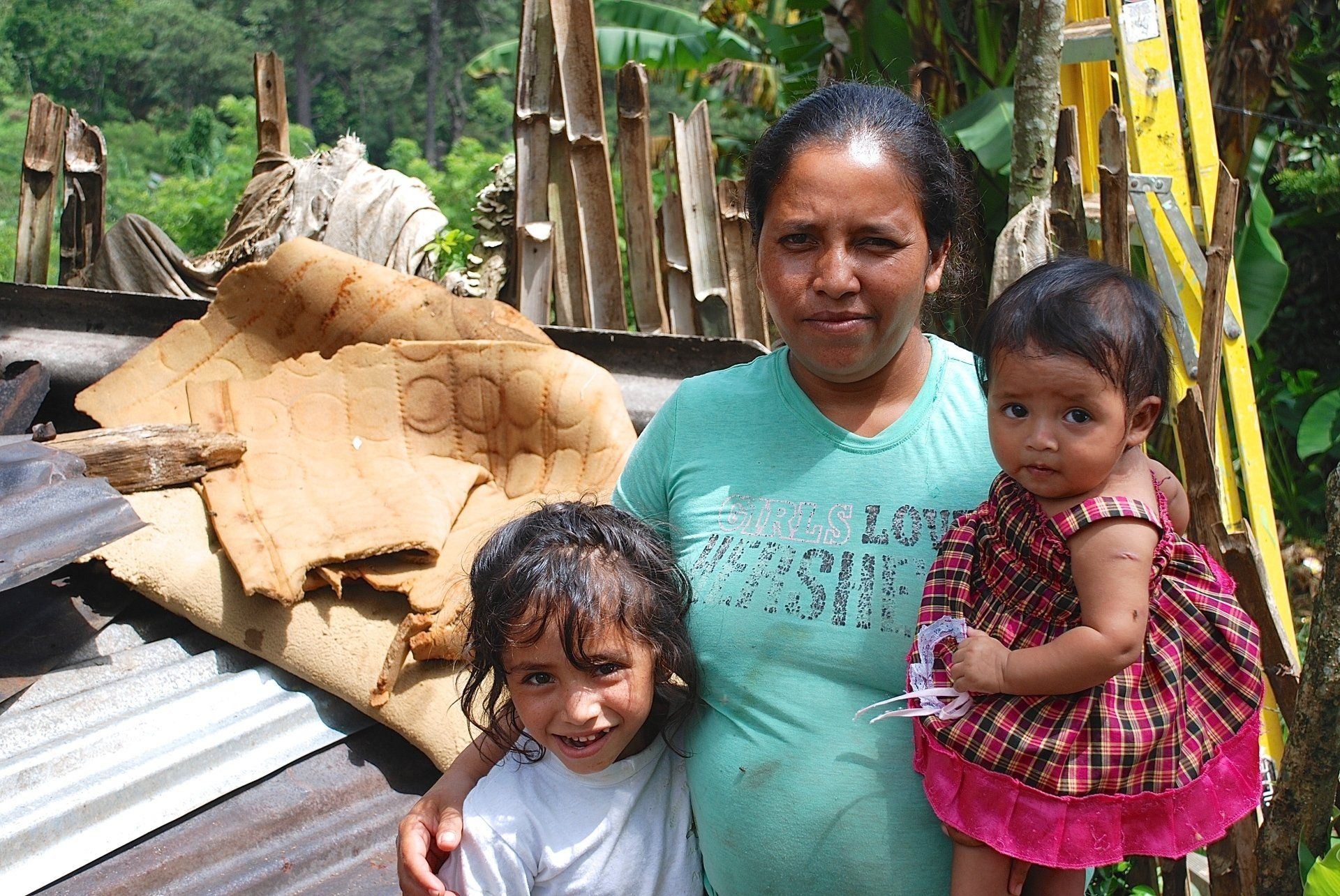 A mother and her two children in front of a destroyed building.