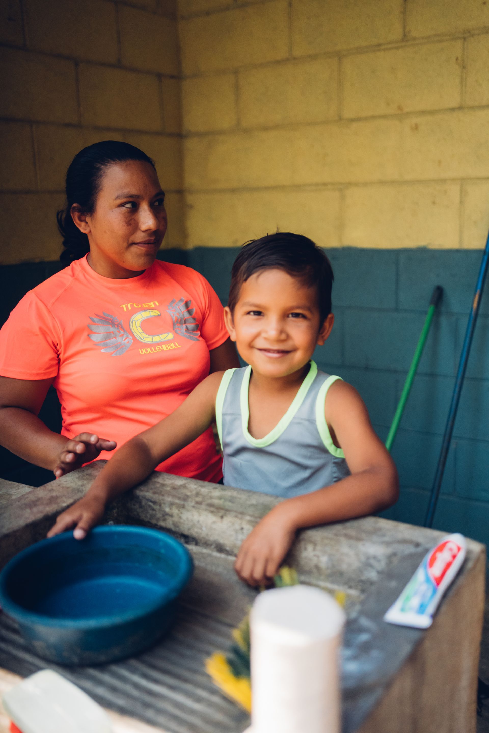 A woman and a little boy washing dishes in a sink.