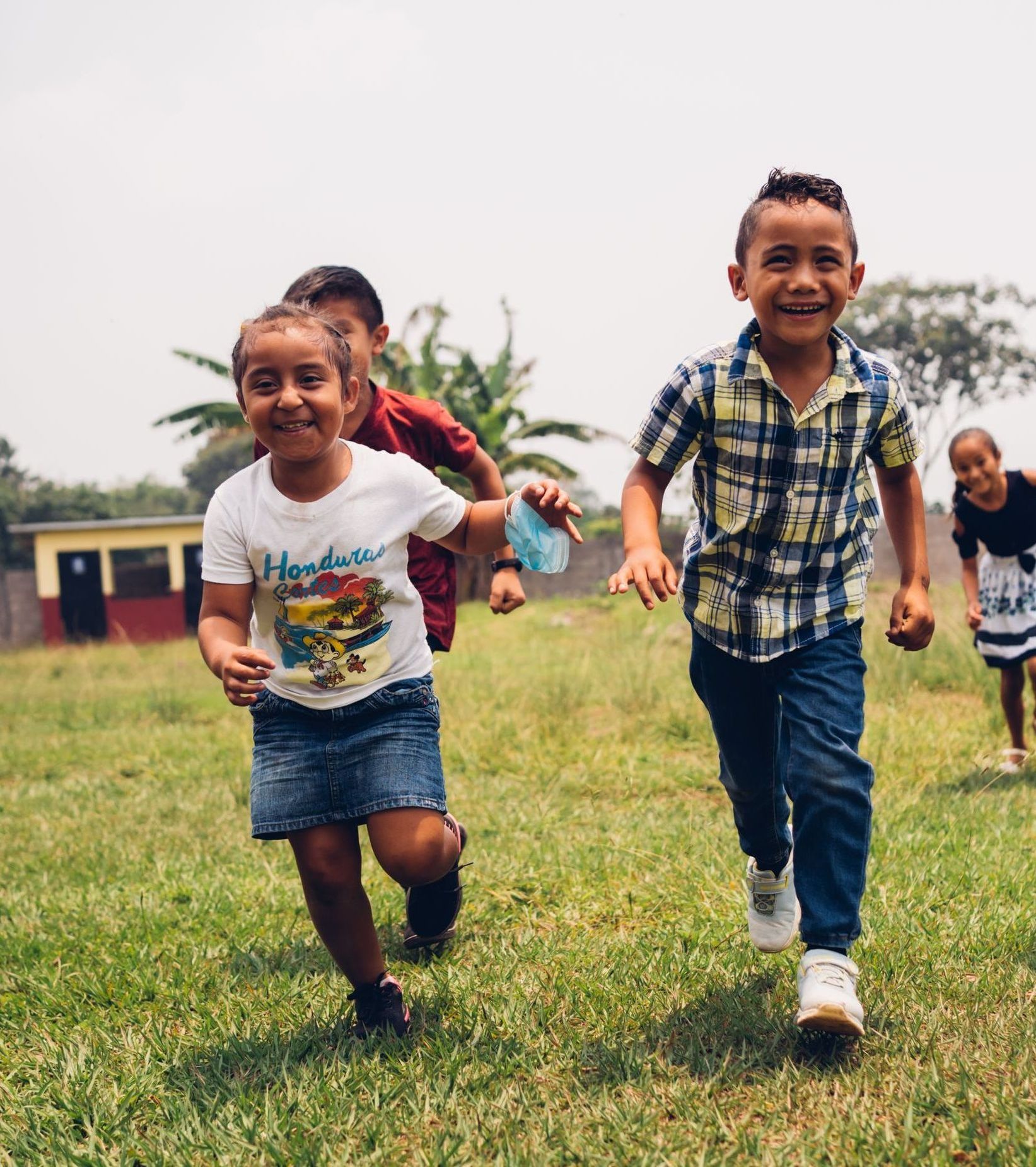 Children laugh as they run through a field.