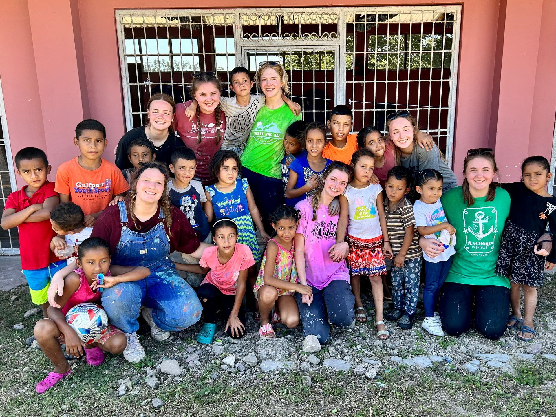 Team members pose with Honduran children in front of a school.