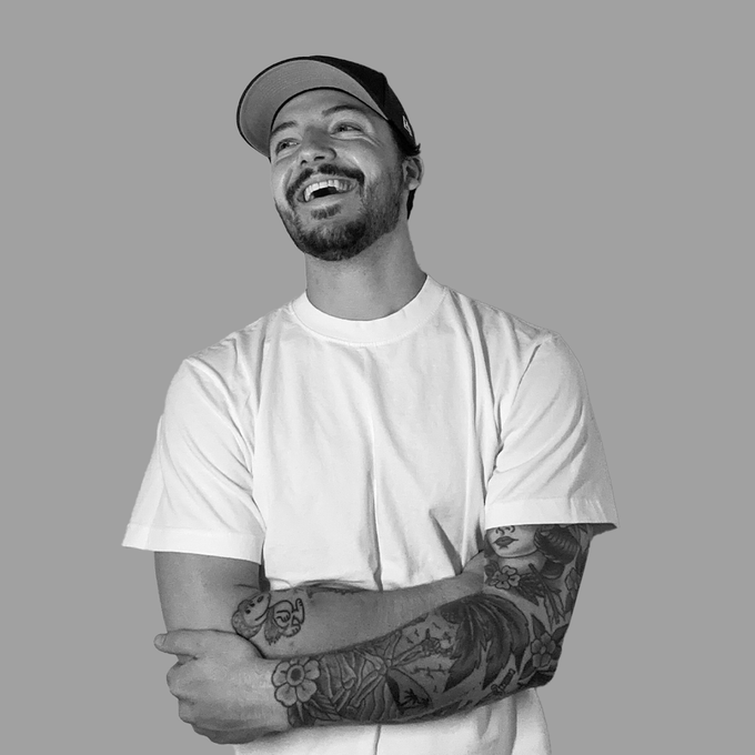 a man with tattoos wearing a hat and smiling