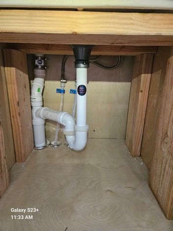 Industrial pump station featuring metal pipes with blue valves and gauges inside a well-lit room.