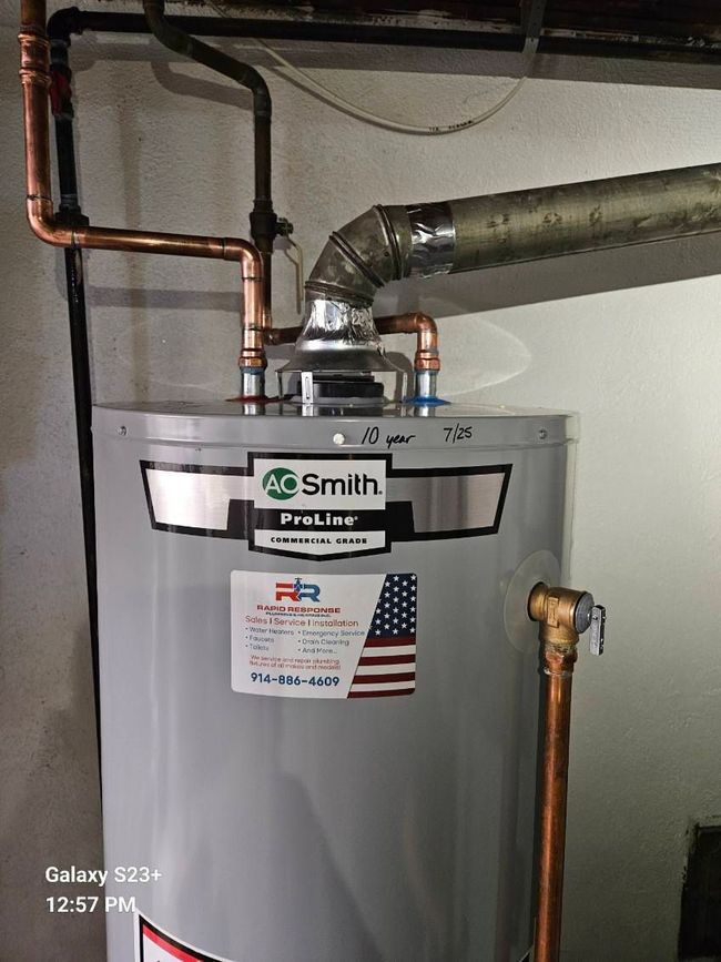 A technician uses a screwdriver to service a multi-stage water filtration system installed under a sink.