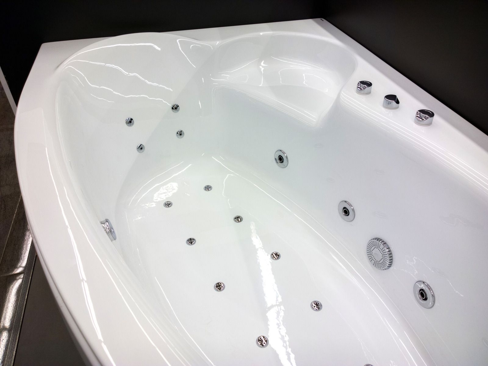 White, oval-shaped jetted whirlpool bathtub with chrome fixtures and jets installed in a bathroom setting.