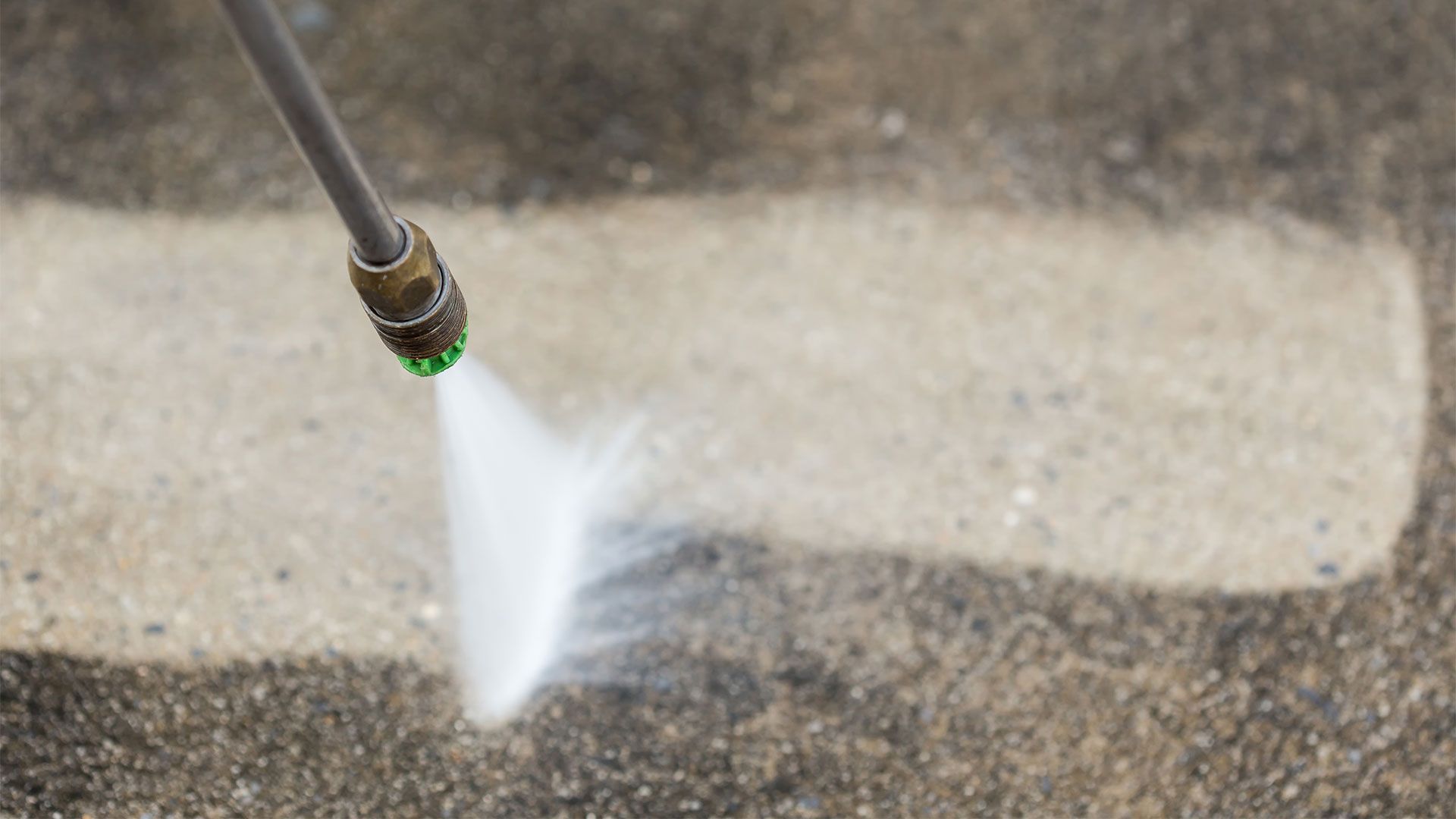 A person is using a high pressure washer to clean a concrete floor.