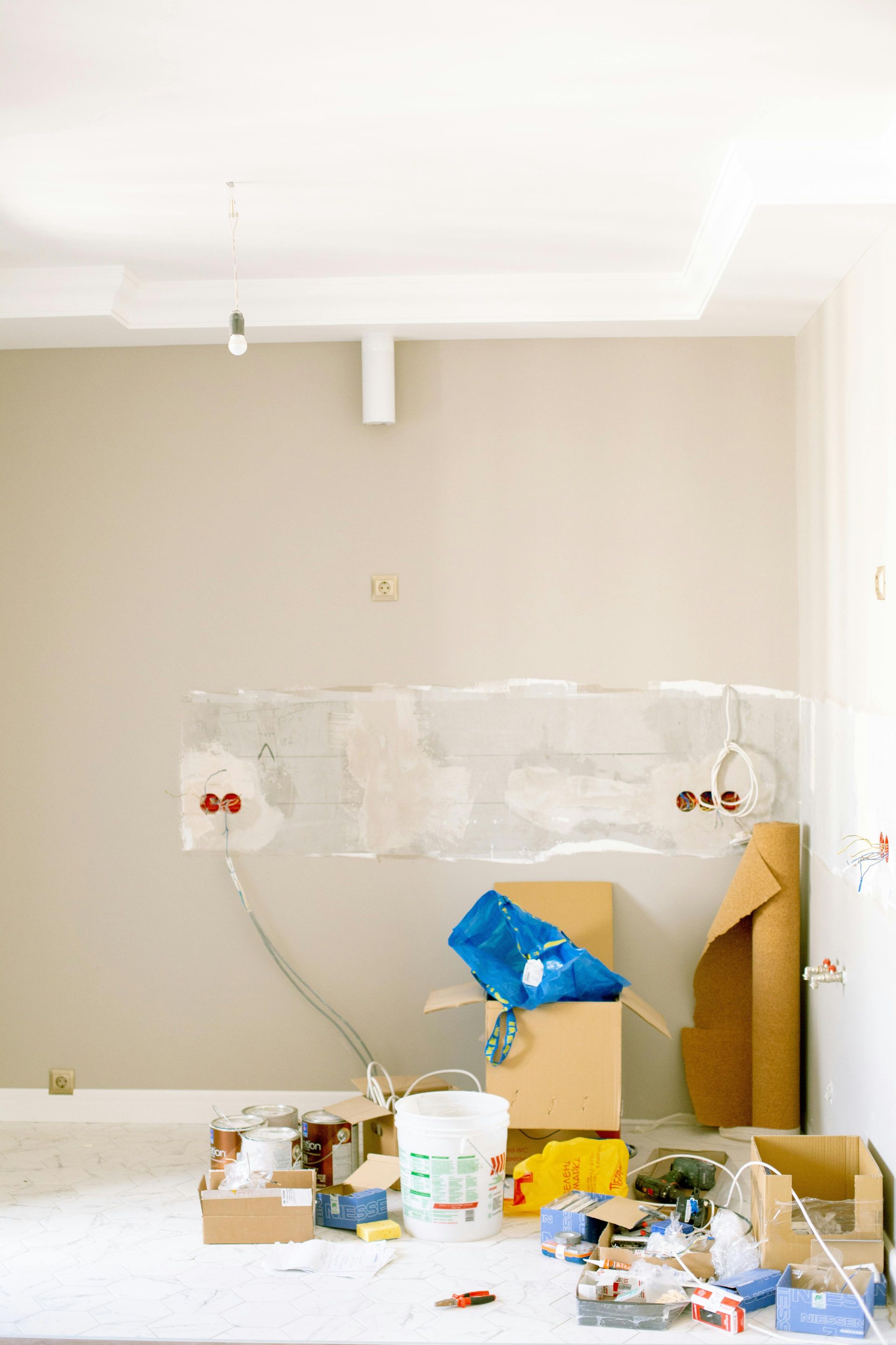 A messy room with a bucket of paint and boxes on the table.
